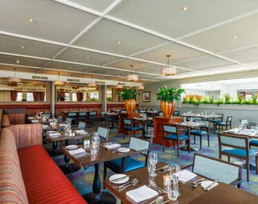 Bright, spacious hotel dining area with cosy seating, elegant decor, and lush greenery inviting guests to enjoy delightful meals.