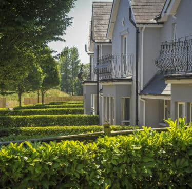 Elegant hotel exterior with lush hedges and balcony views, inviting guests to relax in serene surroundings.