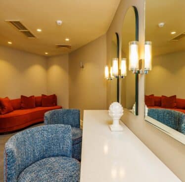 Stylish hotel lounge with plush red sofa, chic lighting, mirrors, and cosy seating for a luxurious and relaxing stay.