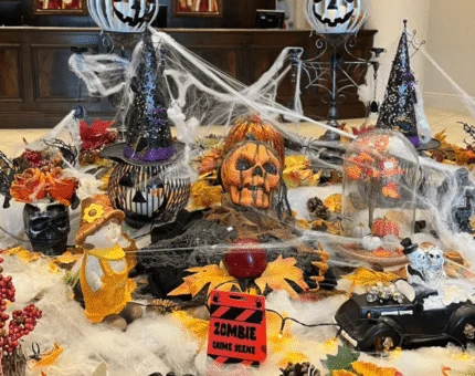 A festive hotel lobby with Halloween-themed decor featuring pumpkins, cobwebs, and autumn leaves, creating a welcoming atmosphere.