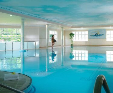 Elegant indoor pool with serene lighting, lush plants, and cosy loungers, perfect for relaxed hotel stays and refreshing swims.