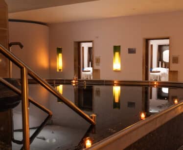 Luxurious spa area with a serene pool, candlelit ambiance, and cosy treatment rooms at a charming hotel in Britain.