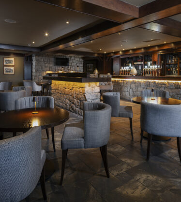Elegant hotel bar with cosy seating, stone accents, ambient lighting, offering a relaxing atmosphere for guests.