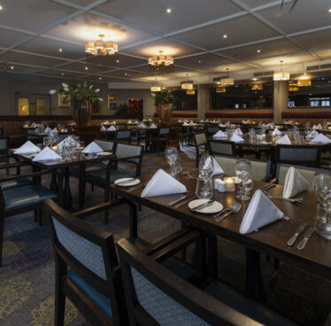 Elegant hotel dining room with neatly set tables, soft lighting, and inviting ambience, ideal for a fine dining experience.