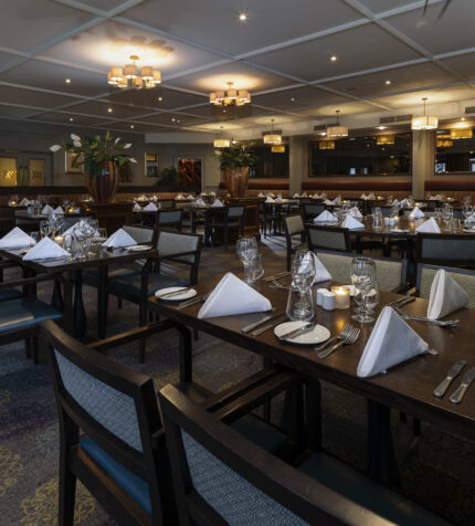 Elegant hotel dining room with neatly set tables, soft lighting, and inviting ambience, ideal for a fine dining experience.