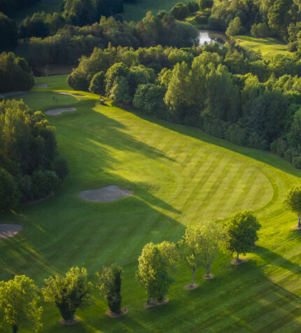 Scenic golf course view with lush green fairways, sand bunkers, and surrounding woodland, perfect for relaxation.