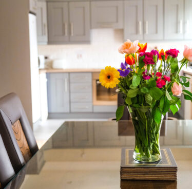 Stylish kitchen with fresh flowers and elegant seating, offering a cosy dining experience at a luxury hotel suite.