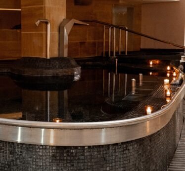 Luxurious indoor spa pool with ambient lighting, elegant tiled walls, soothing water jets, and relaxing atmosphere.
