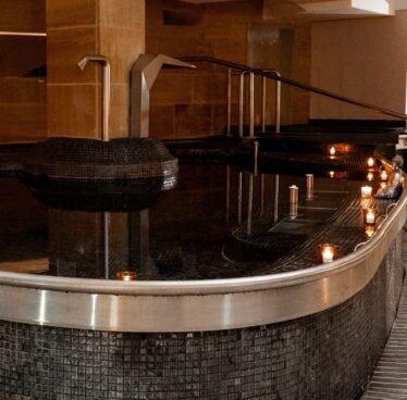 Luxurious indoor spa pool with ambient lighting, elegant tiled walls, soothing water jets, and relaxing atmosphere.