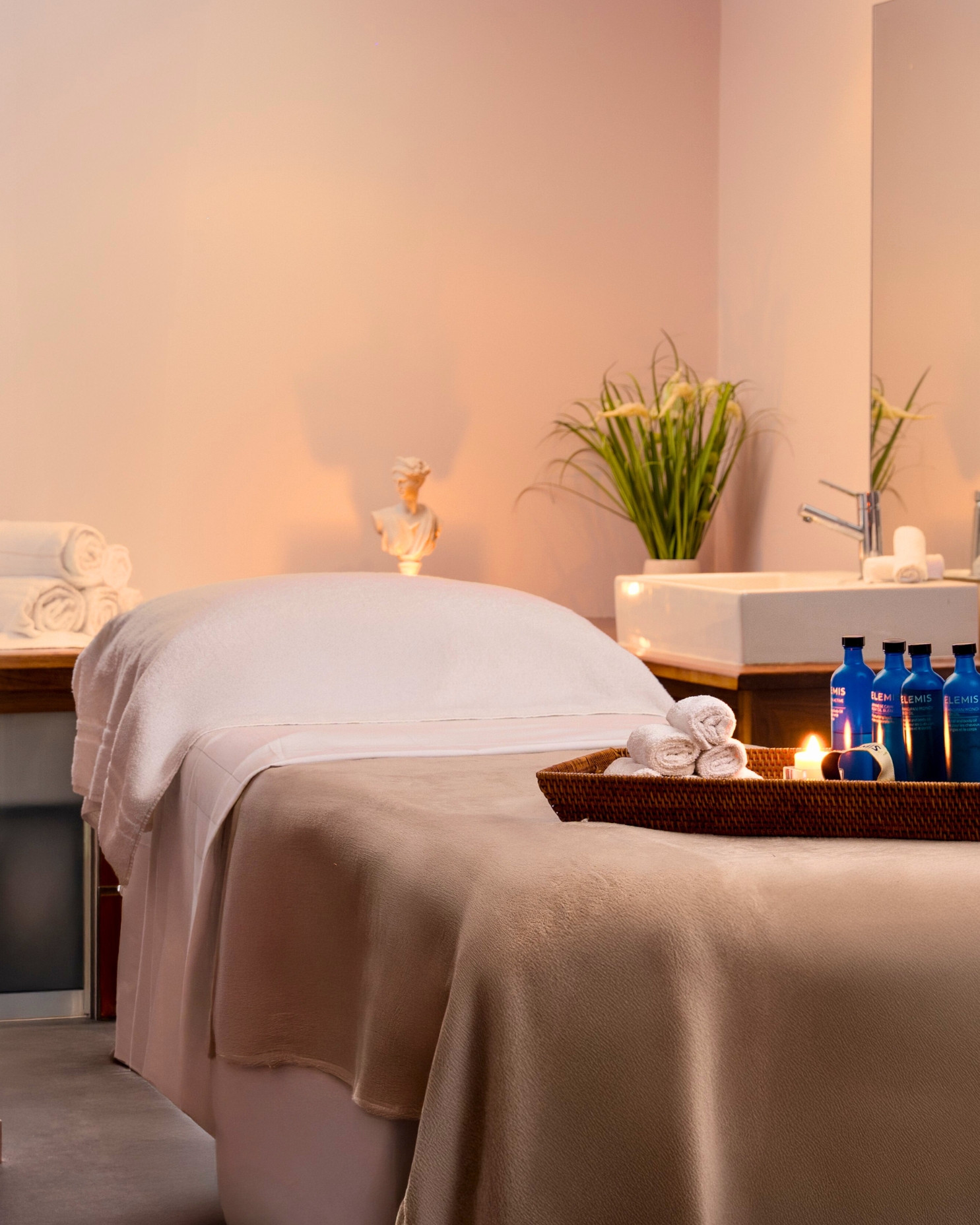 Relaxing hotel spa with plush massage bed, soft linens, candles, and luxury products, offering a serene wellness experience.