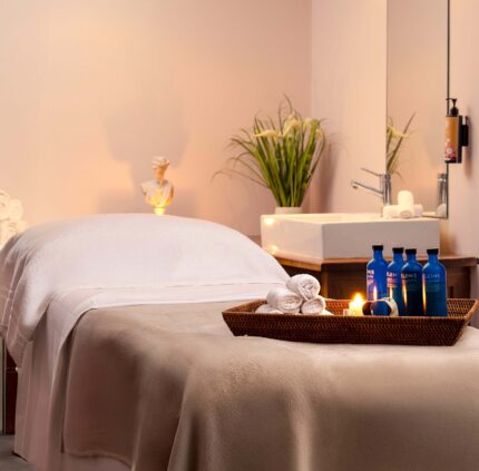 Relaxing spa room with massage bed, cosy towels, candles, and luxury toiletries in serene hotel setting.