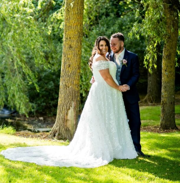 Couple smiling in a lush garden setting during a sunny wedding at our luxury hotel, surrounded by scenic greenery.