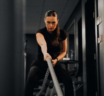 Guest enjoying an energising workout in modern hotel gym with battle ropes, dim lighting, and high-end fitness equipment.