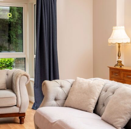 Elegant hotel suite lounge with plush sofas, garden view, and soft lighting for a cosy, relaxing stay.