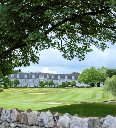 Luxury hotel with lush golf course views, framed by trees and serene landscape, perfect for relaxing retreats.