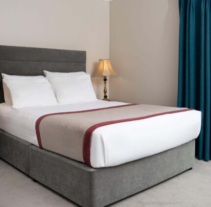 Spacious hotel room with king-sized bed, elegant lamps, and balcony view, offering comfort and relaxation in prime location.