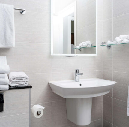 Stylish hotel bathroom with modern sink, plush towels, and mirror, offering comfort and luxury for guests.