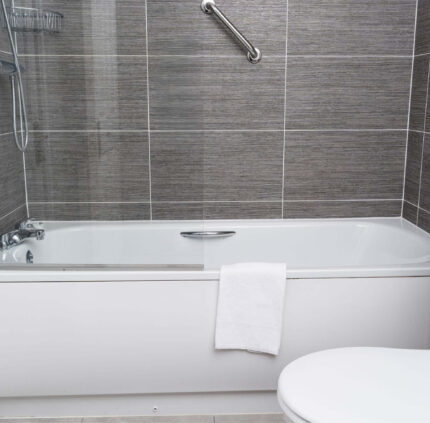 Luxurious hotel bathroom with modern bathtub, plush towels, sleek tiles, and elegant chrome fixtures.