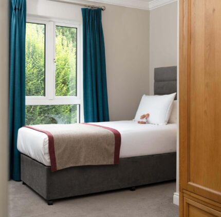 Cosy hotel room with a plush double bed, inviting natural light through large window, perfect for a relaxing stay.