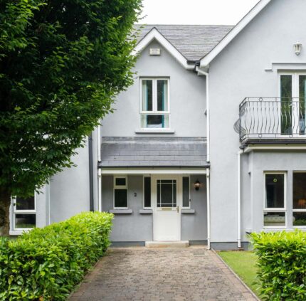Charming hotel exterior with balcony, lush greenery, and welcoming entrance, offering a serene countryside stay.