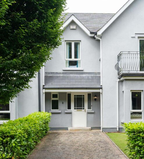 Charming hotel exterior with balcony, lush greenery, and welcoming entrance, offering a serene countryside stay.
