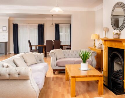 Spacious hotel suite with cosy sofas, elegant fireplace, and chic dining area, ideal for relaxing getaways.