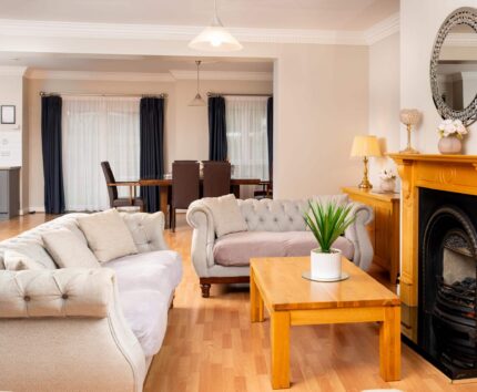 Spacious hotel suite with cosy sofas, elegant fireplace, and chic dining area, ideal for relaxing getaways.