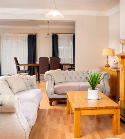Spacious hotel suite with cosy sofas, elegant fireplace, and chic dining area, ideal for relaxing getaways.