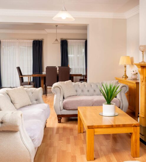 Spacious hotel suite with cosy sofas, elegant fireplace, and chic dining area, ideal for relaxing getaways.