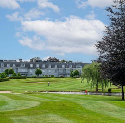 Elegant hotel with lush golf course, manicured gardens, and clear skies, ideal for leisure and relaxing retreats.