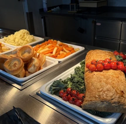 Delicious hotel buffet with Yorkshire puddings, vegetable roast, cherry tomatoes, and mashed potatoes in elegant setting.