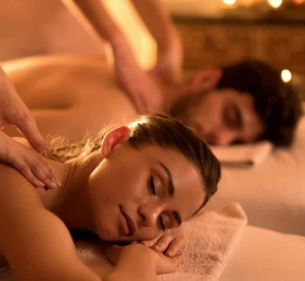 Couple enjoying a relaxing back massage on spa beds with candlelight, plush towels and soothing ambience at hotel spa